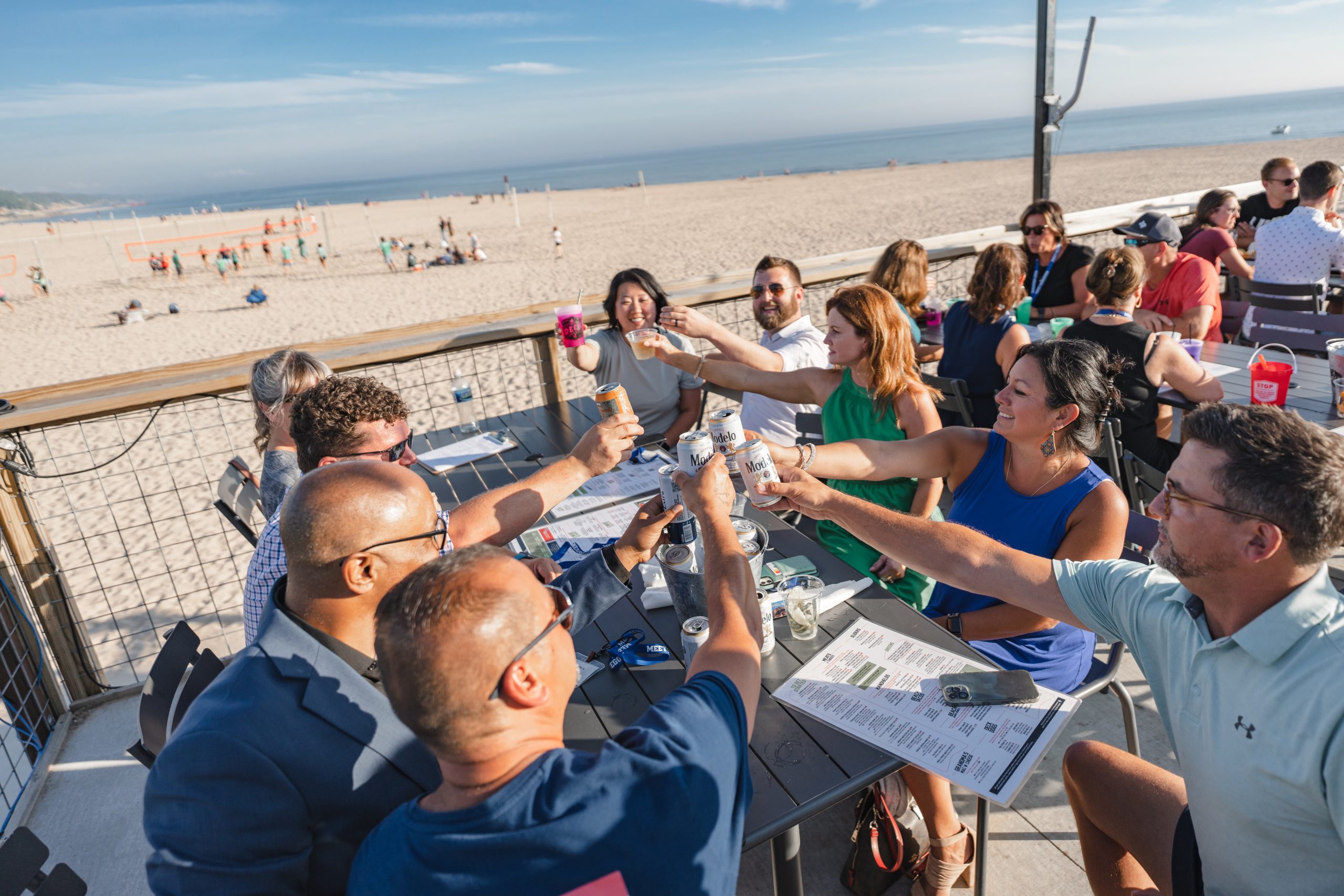 Group of people toasting at beach restaurant.