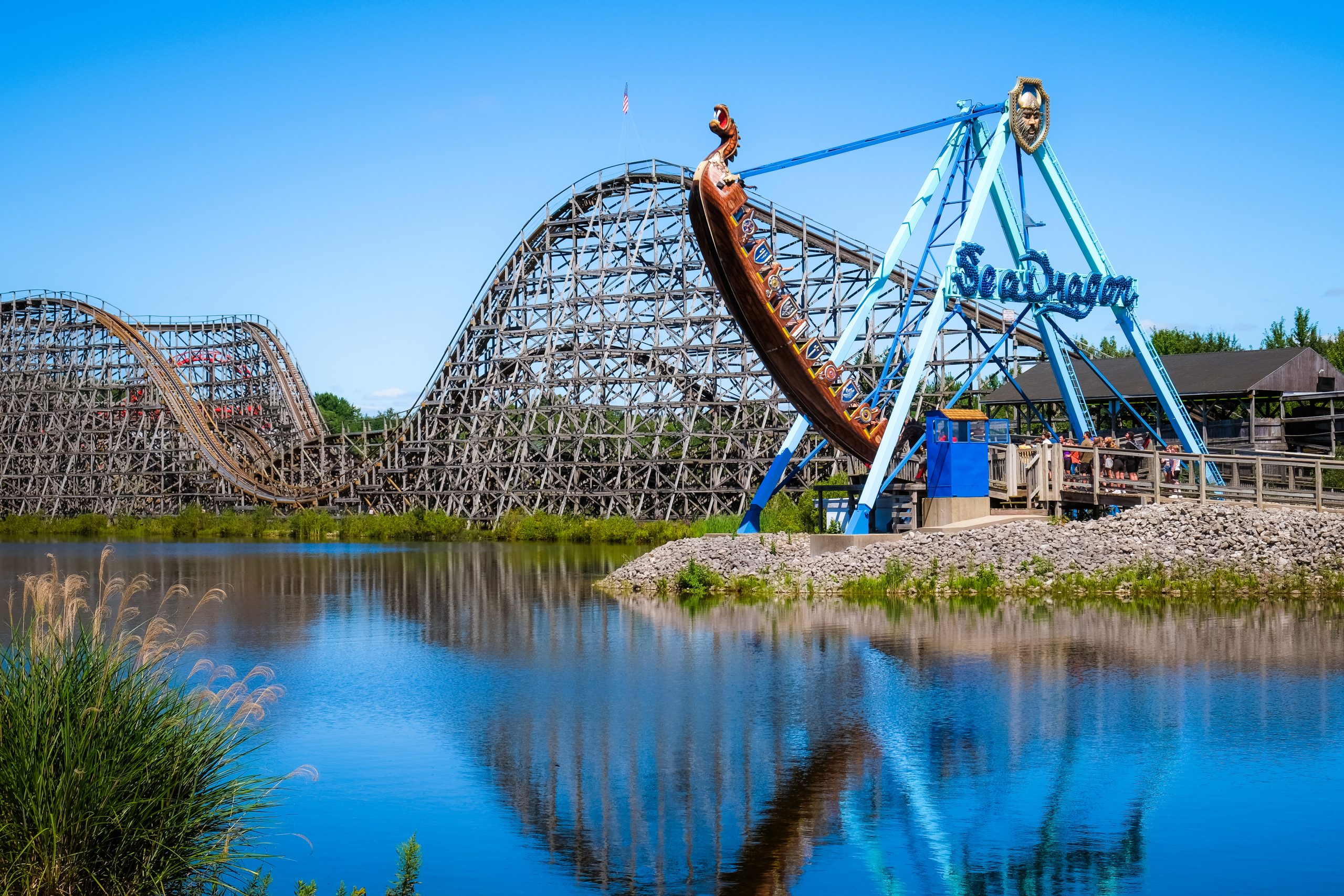 rollercoaster and seadragon rides are reflected in small lake at Michigan's Adventure amusement park