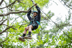 child on zipline covered by canopy of green leaves 