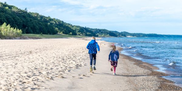 young children running up the coastline of lake michigan