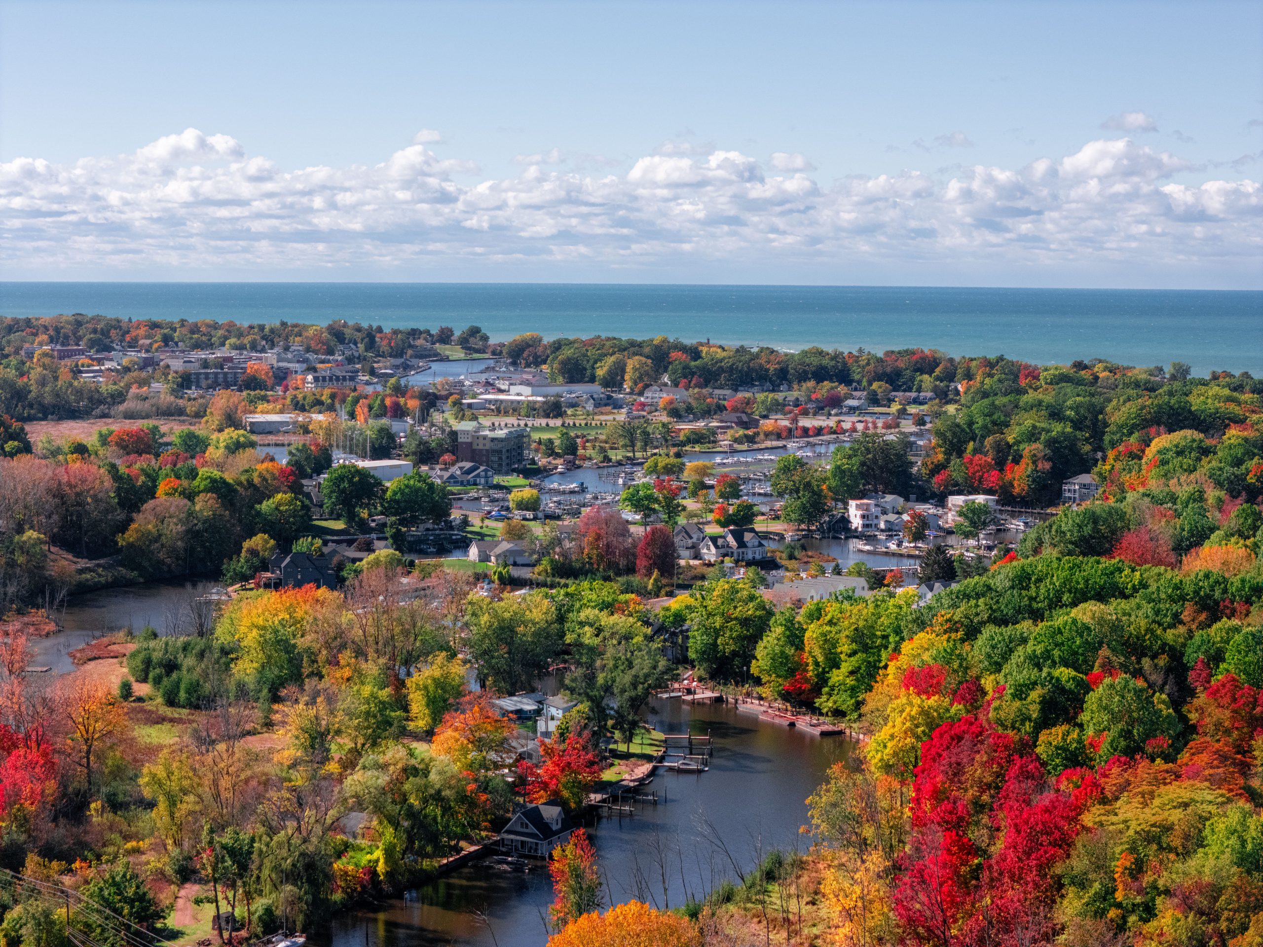 Aerial photo of South Haven displaying fall colors in the trees with lake Michigan shining blue on the horizon.