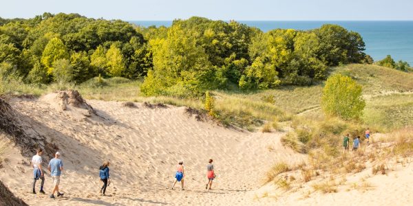 A photo shows a group of people strolling in the dunes on a sunny spring day!