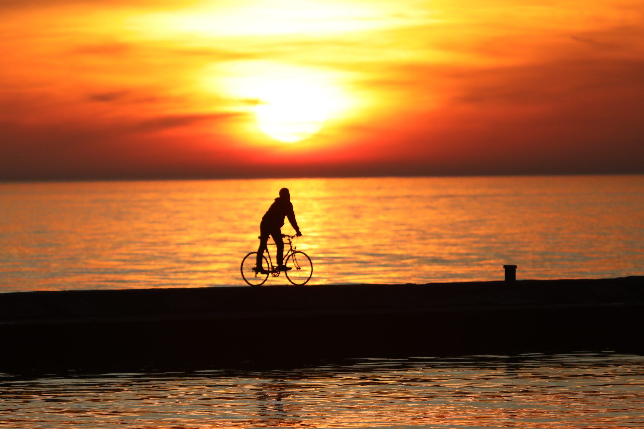 A biker enjoys a Lake Michigan Sunset on the St. Joseph Lighthouse Pier 